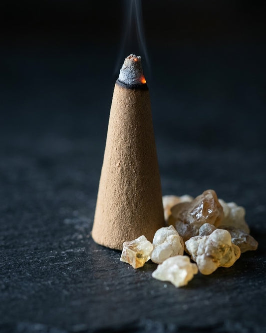 Close-up of a glowing Loban Antar dhoop cone beside loban resin, a thread of smoke rising