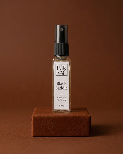 Black Saddle eau de parfum 8 ml glass spray on a cognac leather plinth