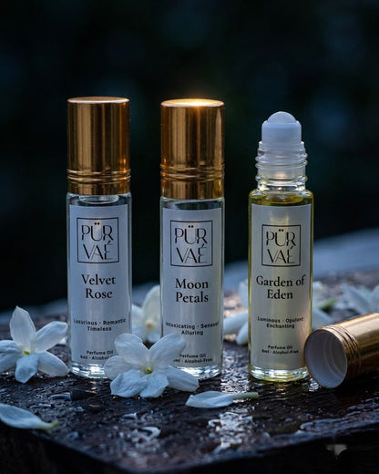 Bloom Trio parfum oils on a wet dark board with jasmine blossoms, the Garden of Eden roller ball showing