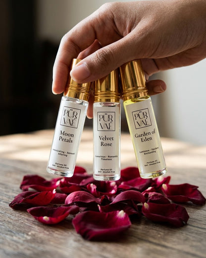 A hand holding the three 6 ml Bloom Trio roll-ons above scattered rose petals to show their size