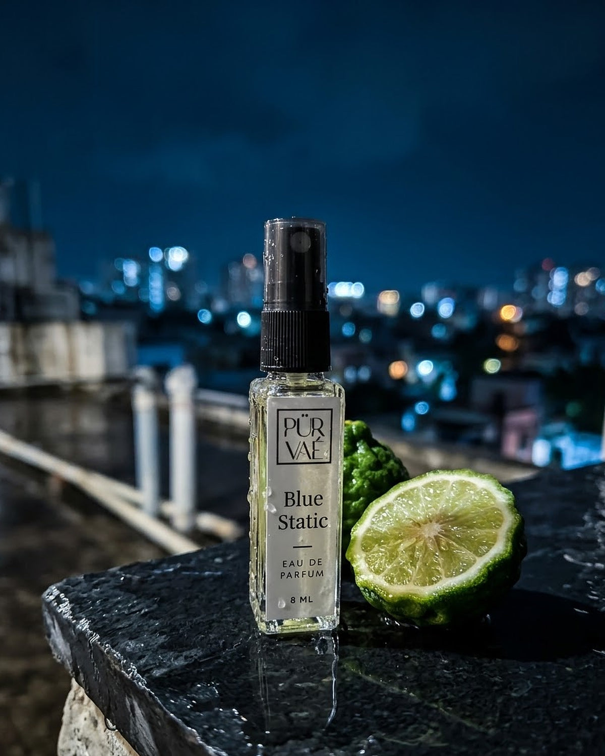 Blue Static on a wet rooftop ledge at night with a halved bergamot
