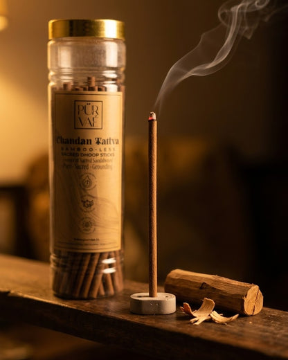 Chandan Tattva dhoop stick burning in its holder on a wooden ledge, Purvae jar in the background