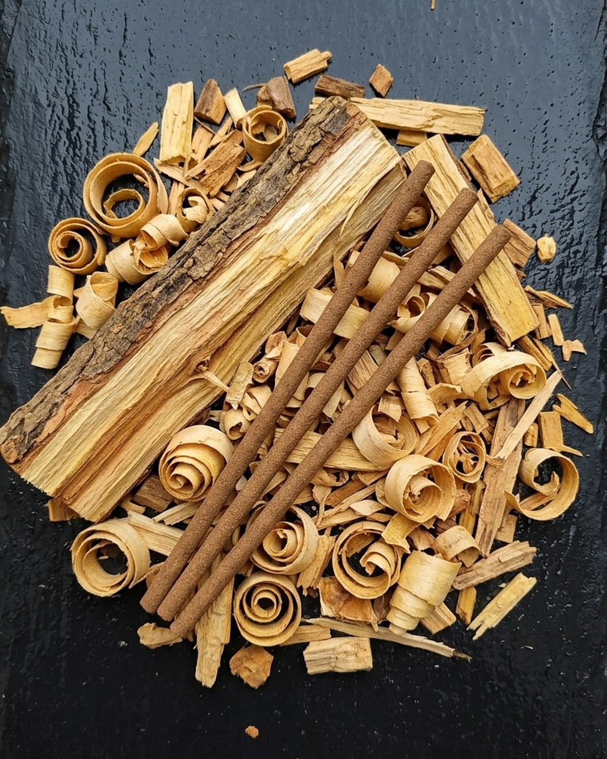 Sandalwood log and shavings that inspire Chandan Tattva dhoop sticks, with three unlit long sticks