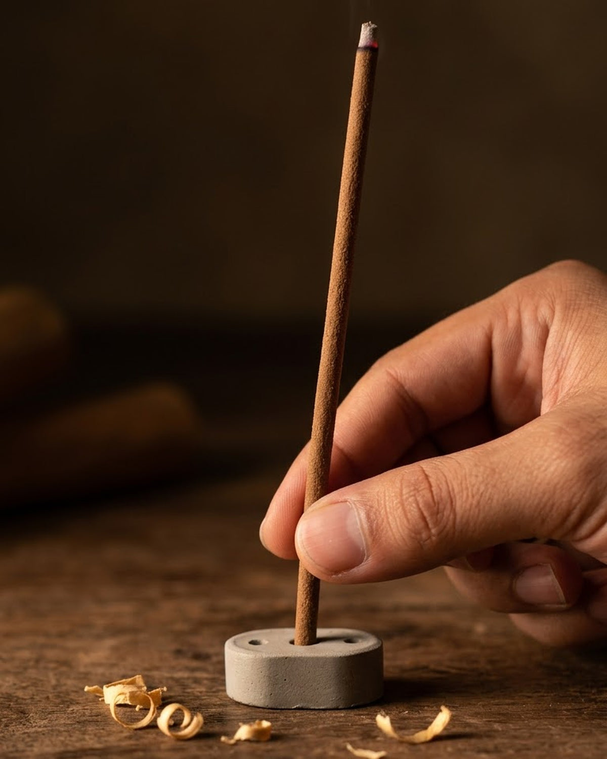 Hand setting a 19 cm Chandan Tattva dhoop stick into its cement holder to show true length