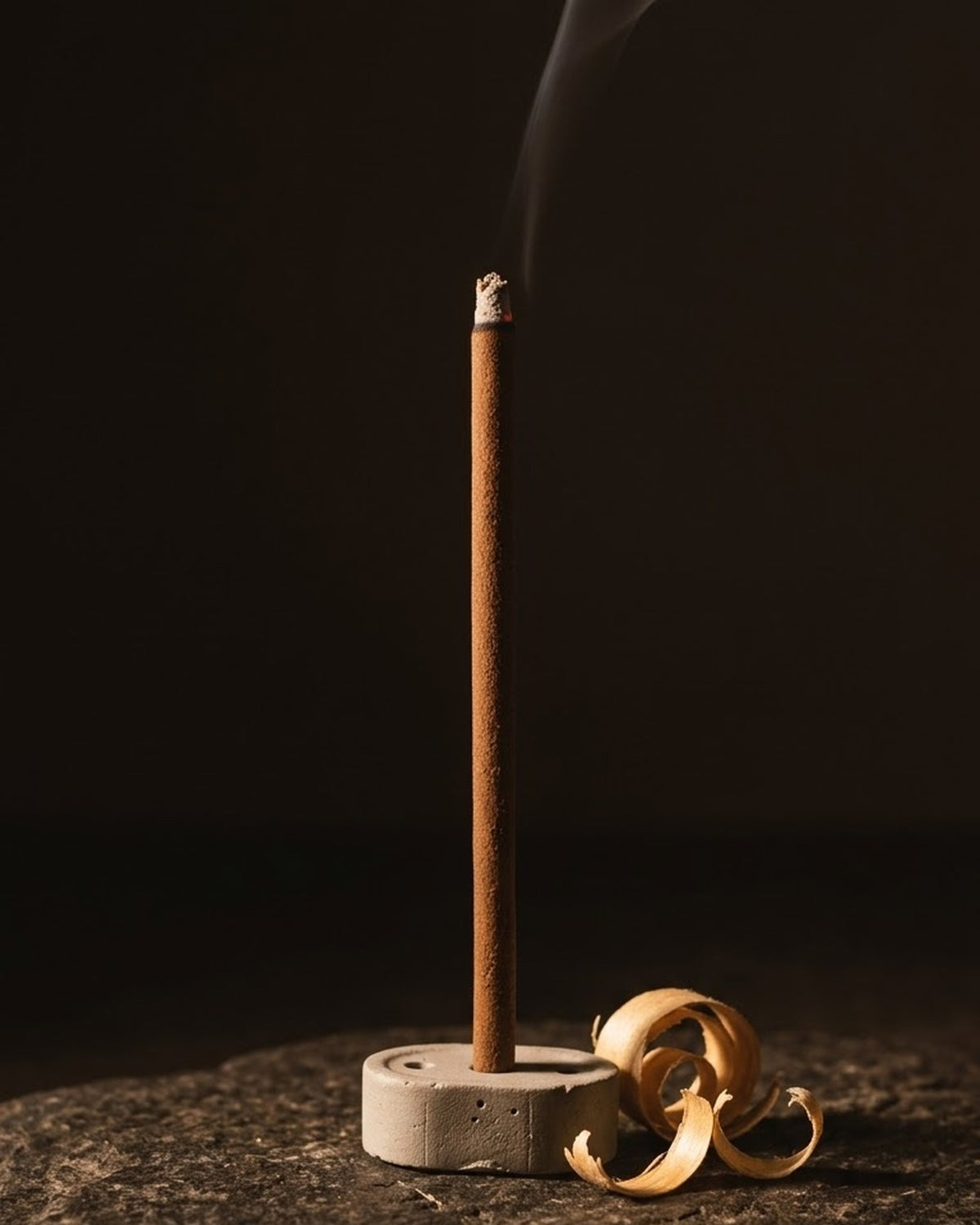 Glowing Chandan Tattva dhoop stick in its holder with smoke rising, beside sandalwood