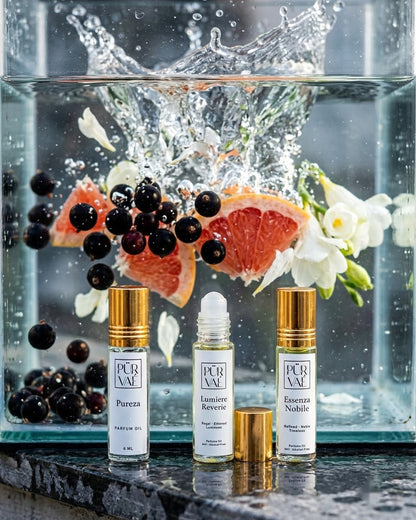 Three Day Trio parfum oils in front of a glass tank where grapefruit, black currants and white blossoms splash into water