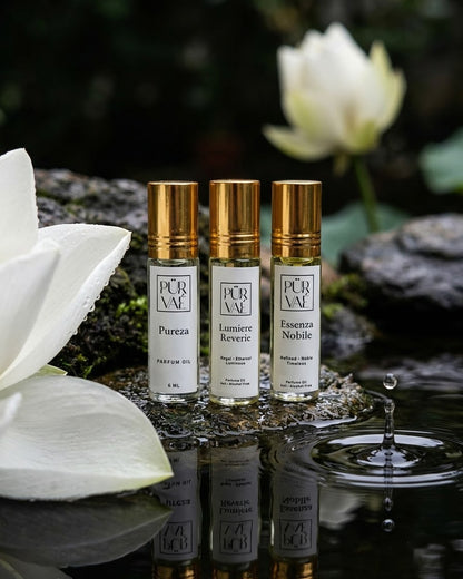 Day Trio parfum oils on a wet stone beside a white lotus, a water drop rippling in the foreground