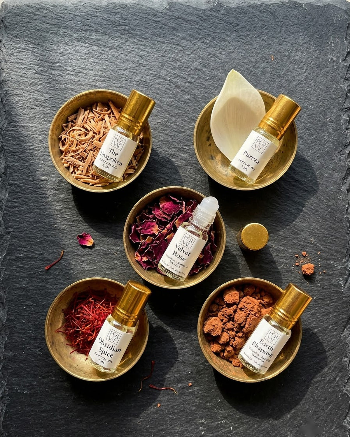 Five 3 ml Purvae parfum oil roll-ons resting in brass katoris with sandalwood, lotus petal, rose petals, saffron and red earth