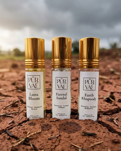 Purvae Earth Trio: Luna Bloom, Eternal Sandal and Earth Rhapsody 6 ml parfum oil roll-ons standing in cracked red earth under a monsoon sky