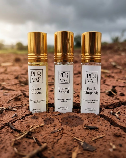 Purvae Earth Trio: Luna Bloom, Eternal Sandal and Earth Rhapsody 6 ml parfum oil roll-ons standing in cracked red earth under a monsoon sky