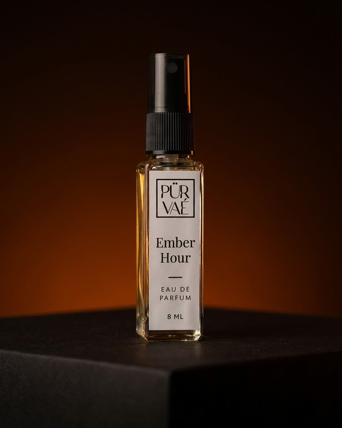 Ember Hour eau de parfum 8 ml glass spray on a dark plinth in ember-orange light