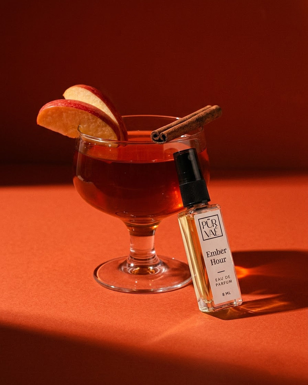 Ember Hour leaning on an amber cocktail glass with apple slices