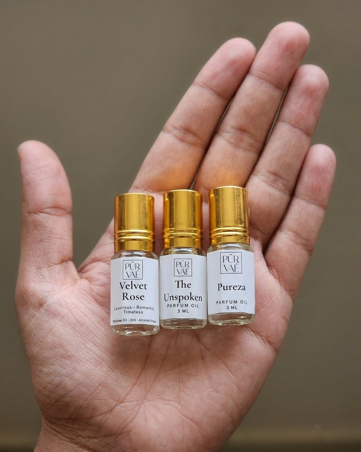 An open palm holding the three small 3 ml First Trio roll-ons to show their size