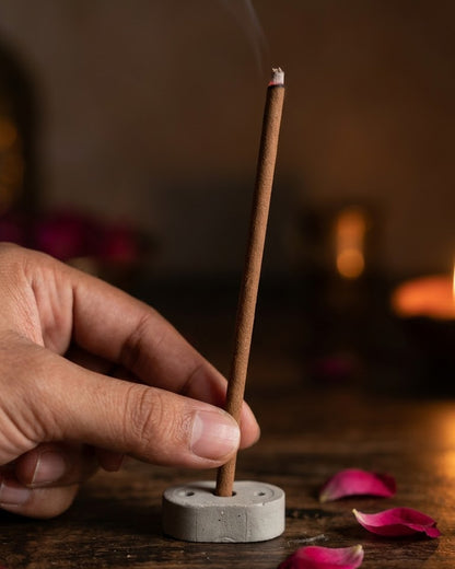 Hand setting a 19 cm Gul Aangan dhoop stick into its cement holder to show true length