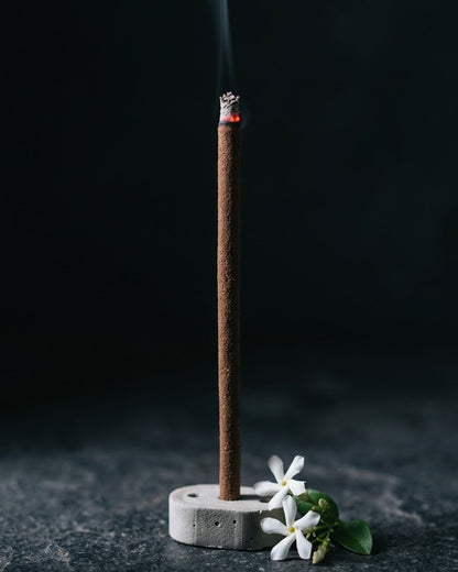 Close-up of a glowing Jasmine Lehar dhoop stick tip with a thread of smoke, beside star jasmine