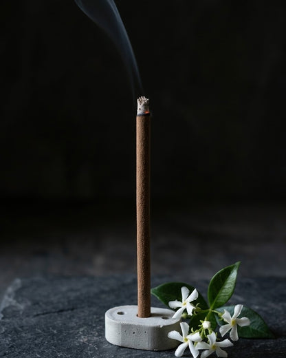 Glowing Jasmine Lehar dhoop stick in its holder with smoke rising, beside star jasmine