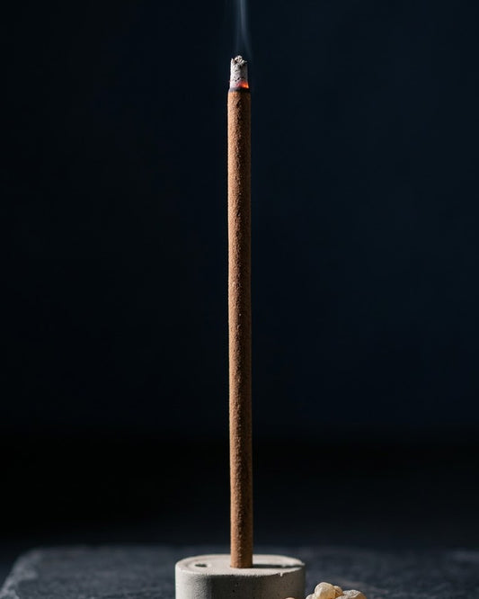 Close-up of a glowing Loban Kaaya dhoop stick tip with a thread of smoke, beside loban crystals