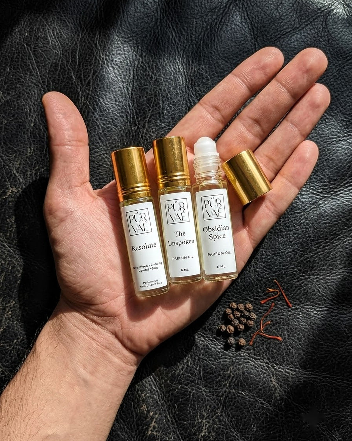 An open palm holding the three 6 ml Night Trio roll-ons to show their size