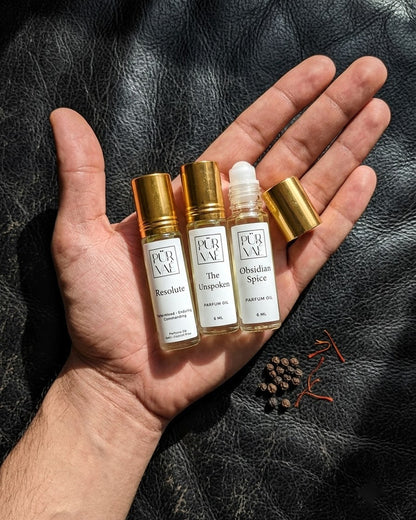 An open palm holding the three 6 ml Night Trio roll-ons to show their size